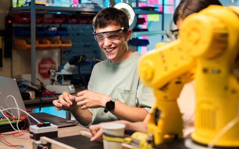 Lernbegleitung von Azubis wirksam gestalten_Für Berufspädagogen und Aus- und Weiterbildungspädagogen Stimmungsvolles Bild von lachendem Azubi in einer Werkstatt als Symbol für gelingende Lernbegleitung in der Aus- und Weiterbildung.